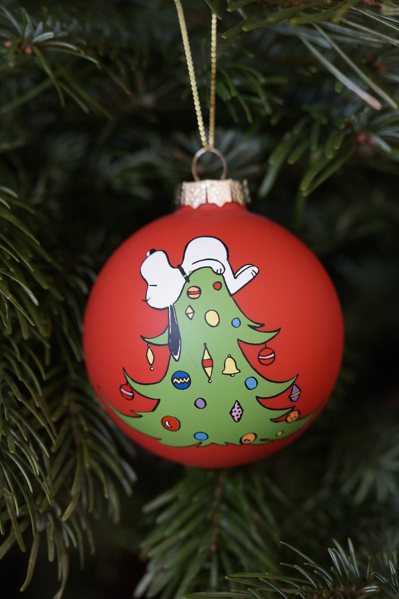 Christmas ornament depicting Snoopy laying on top of a tree